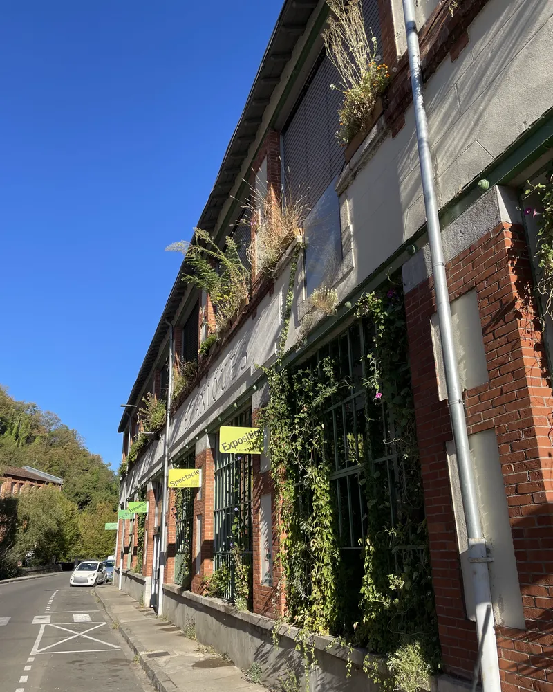 La grünboX aujourd'hui : façade en brique et enduit végétalisée, plantes aux fenêtres, inscription « Constructions mécaniques »