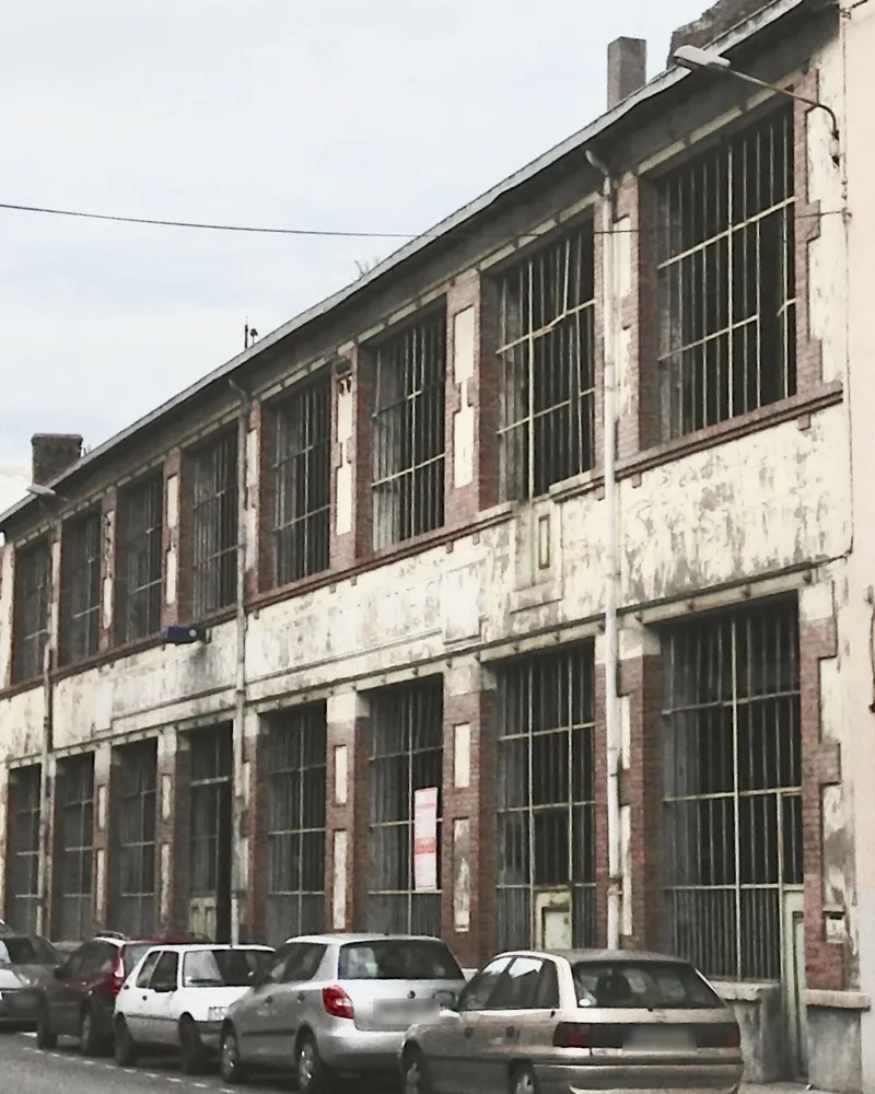 La même façade en 2016, avant les travaux : enduit écaillé, fenêtres grillagées, voitures garées devant