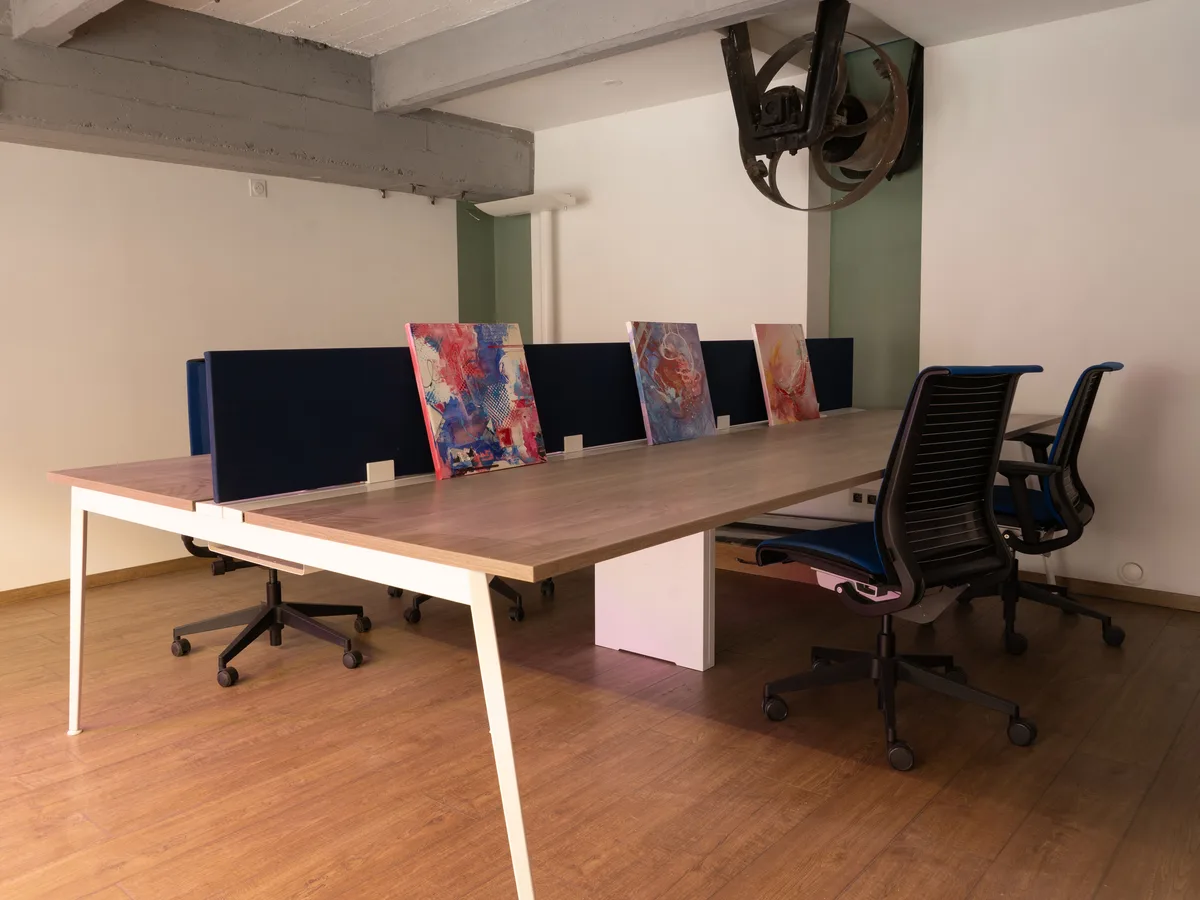 Bureau partagé de la grünboX : grande table, fauteuils et cloisons bleues